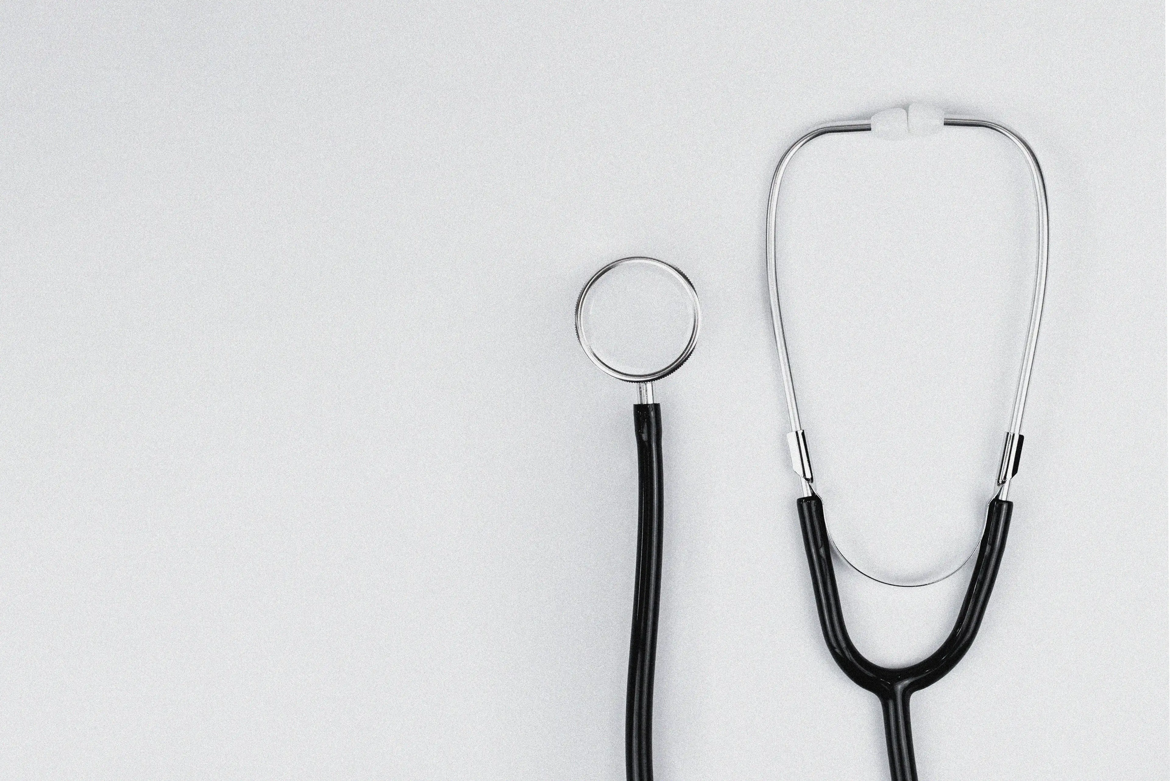  Blue stethoscope and blue pens resting on the pocket of a white medical lab coat, symbolizing healthcare and the medical profession