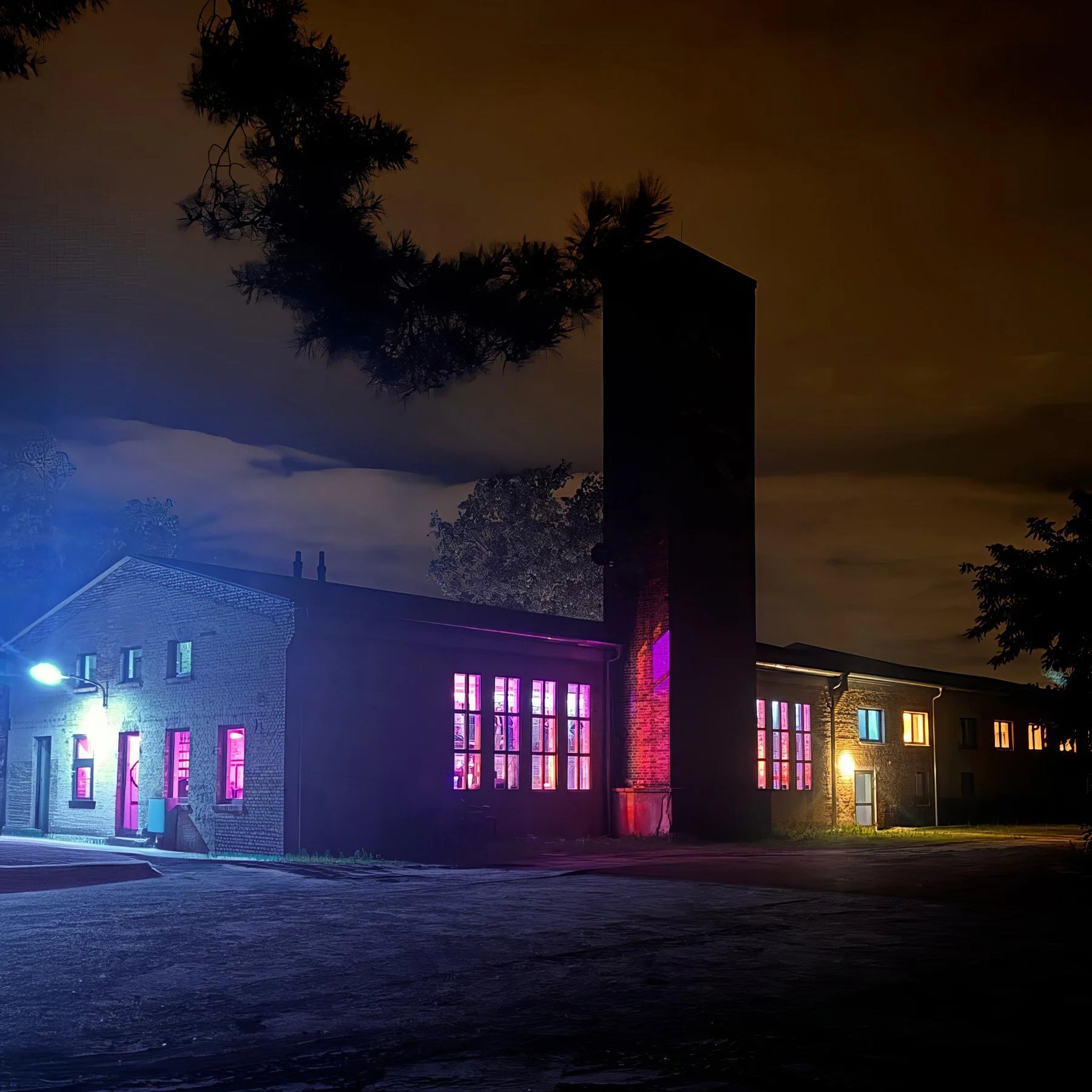 SIGGI Event Venues - Industriecharme trifft moderne Eleganz - Außenansicht bei Nacht mit farbiger Beleuchtung