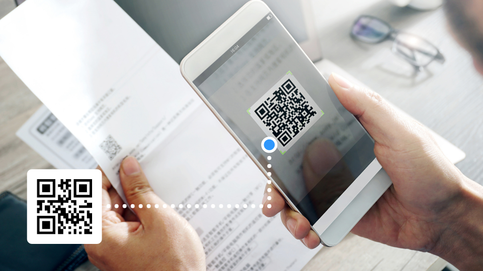 Person scanning a document with a smartphone showing a QR code and a successful scan indicator.