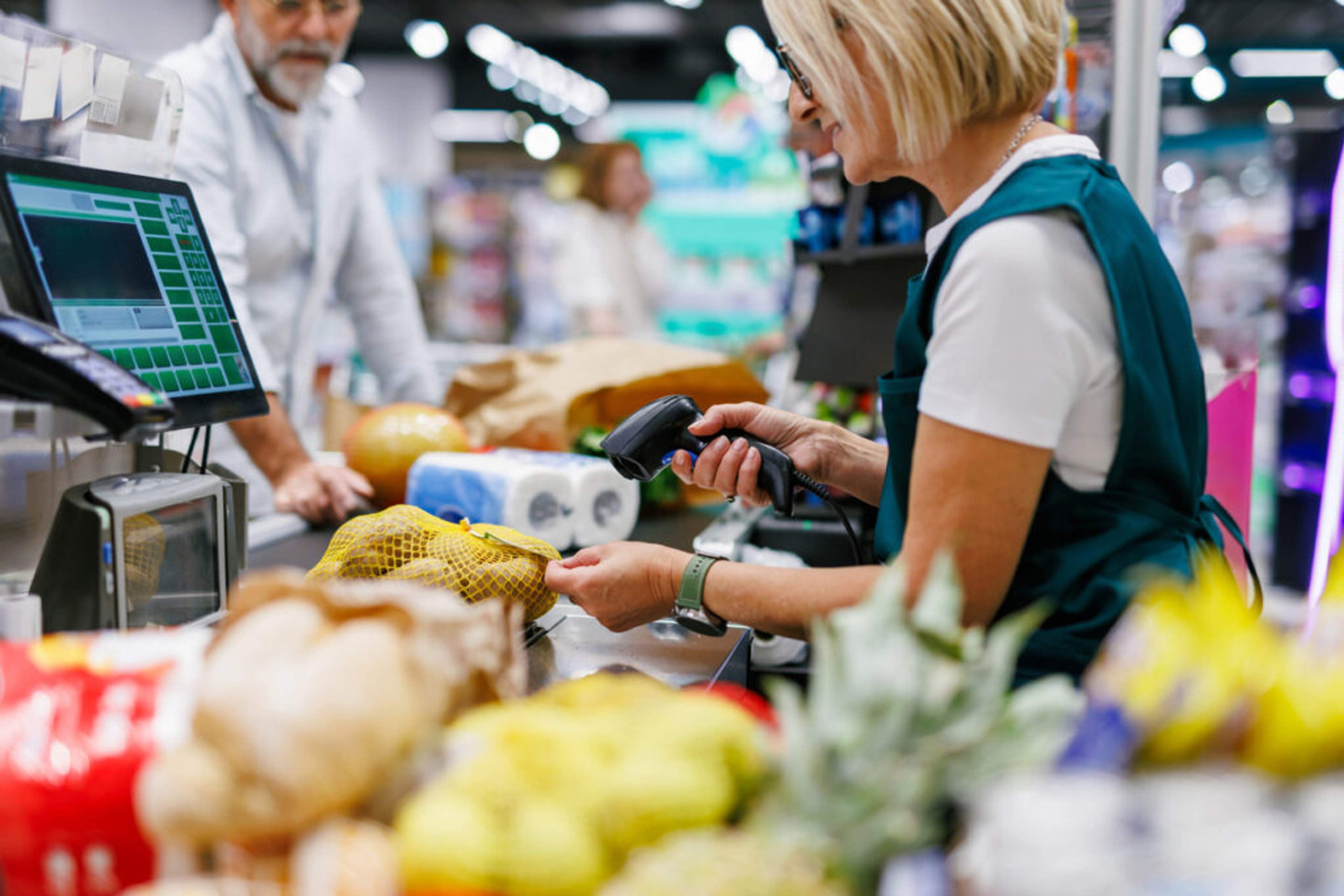 Cashier scanning groceries with a barcode scanner at a supermarket counter
