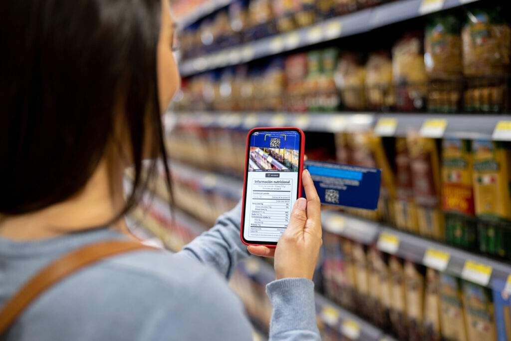 Shopper scanning a QR code on a package with a smartphone in a grocery store