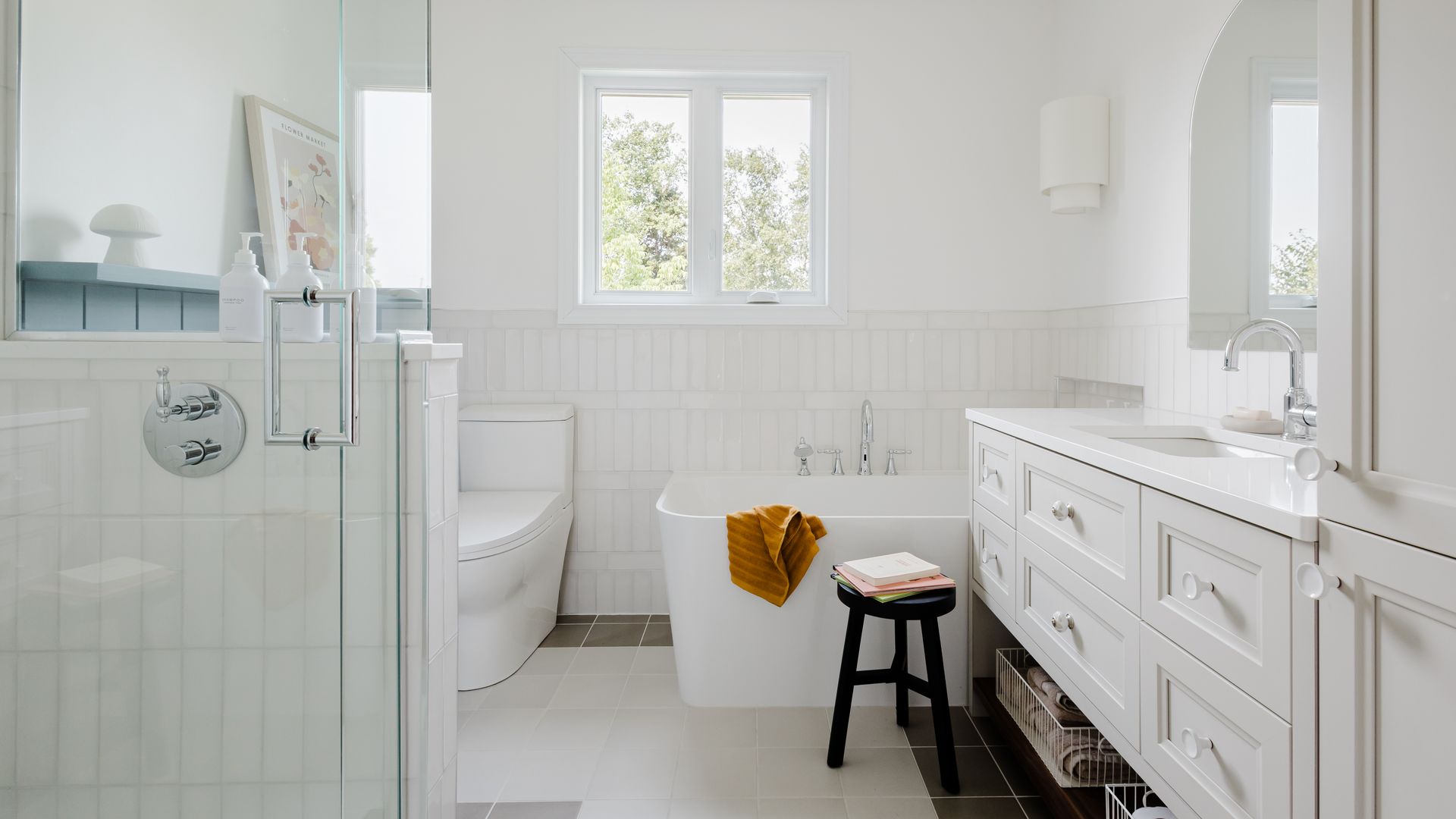 Salle de bain lumineuse, bain en coin, détail de céramique, vanité sur mesure, tuile blanche, lambris bleu, douche en verre, mirroir en arche