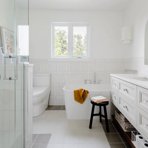 Salle de bain lumineuse, bain en coin, détail de céramique, vanité sur mesure, tuile blanche, lambris bleu, douche en verre, mirroir en arche