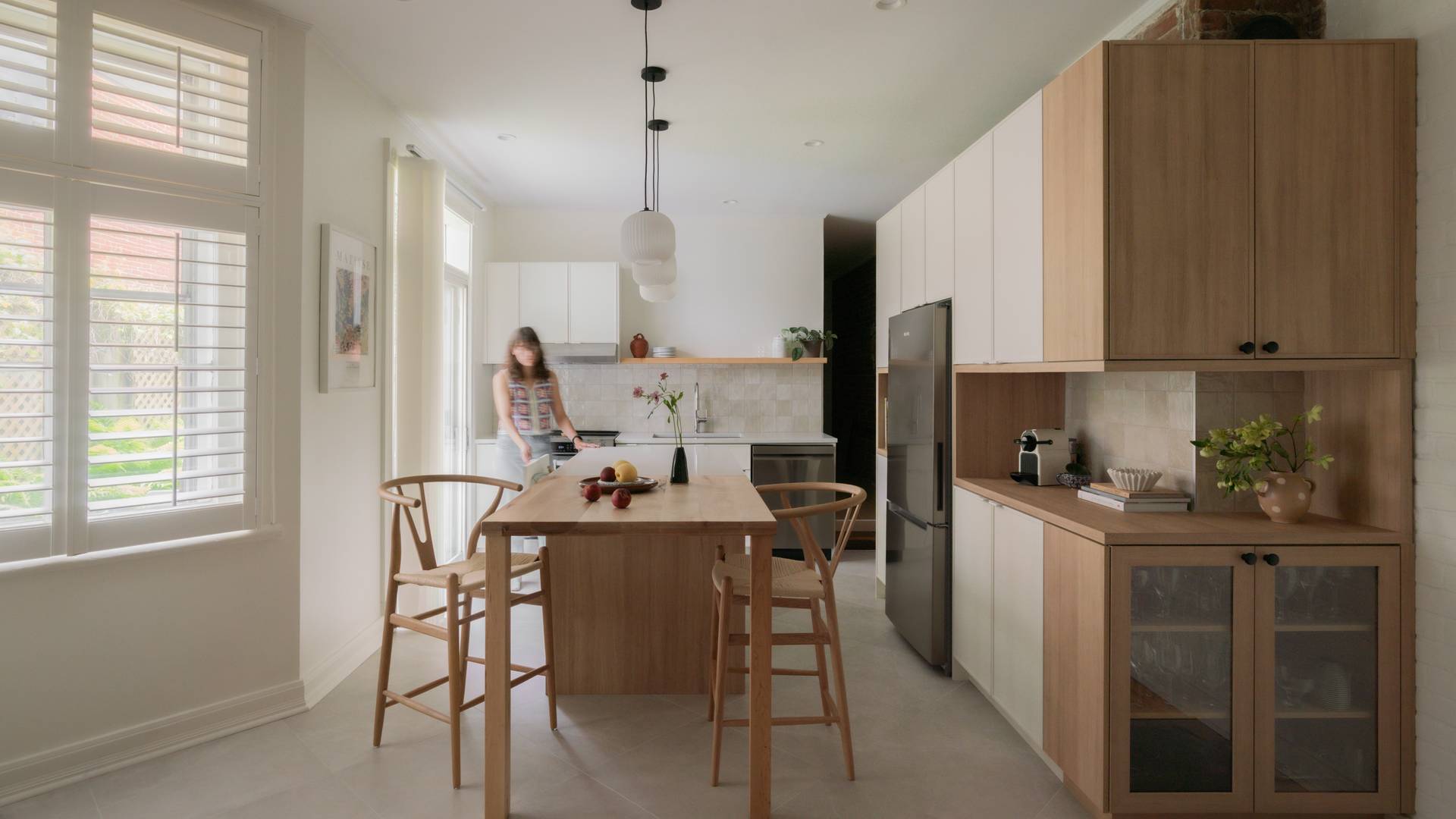 cuisine crème, îlot de bois, comptoir de quartz, tabourets de bois, armoires blanches, armoires bois, dosseret de tuiles carrées, tuiles 24x24 au sol, mur de brique