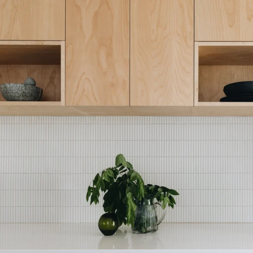 Cuisine moderne, dosseret de tuiles "stick" et armoire de bois, décoration de branche vertes dans un vase en verre