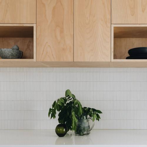 Cuisine moderne, dosseret de tuiles "stick" et armoire de bois, décoration de branche vertes dans un vase en verre