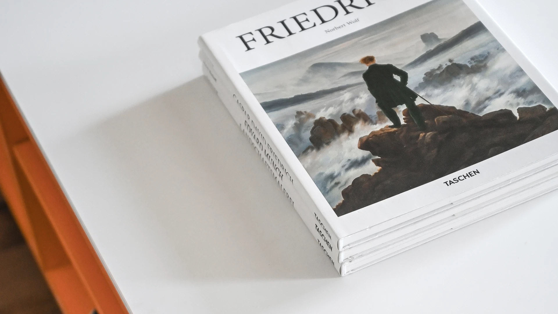 Livre posé sur un meuble de design moderne de couleur orange avec rangement intégré.