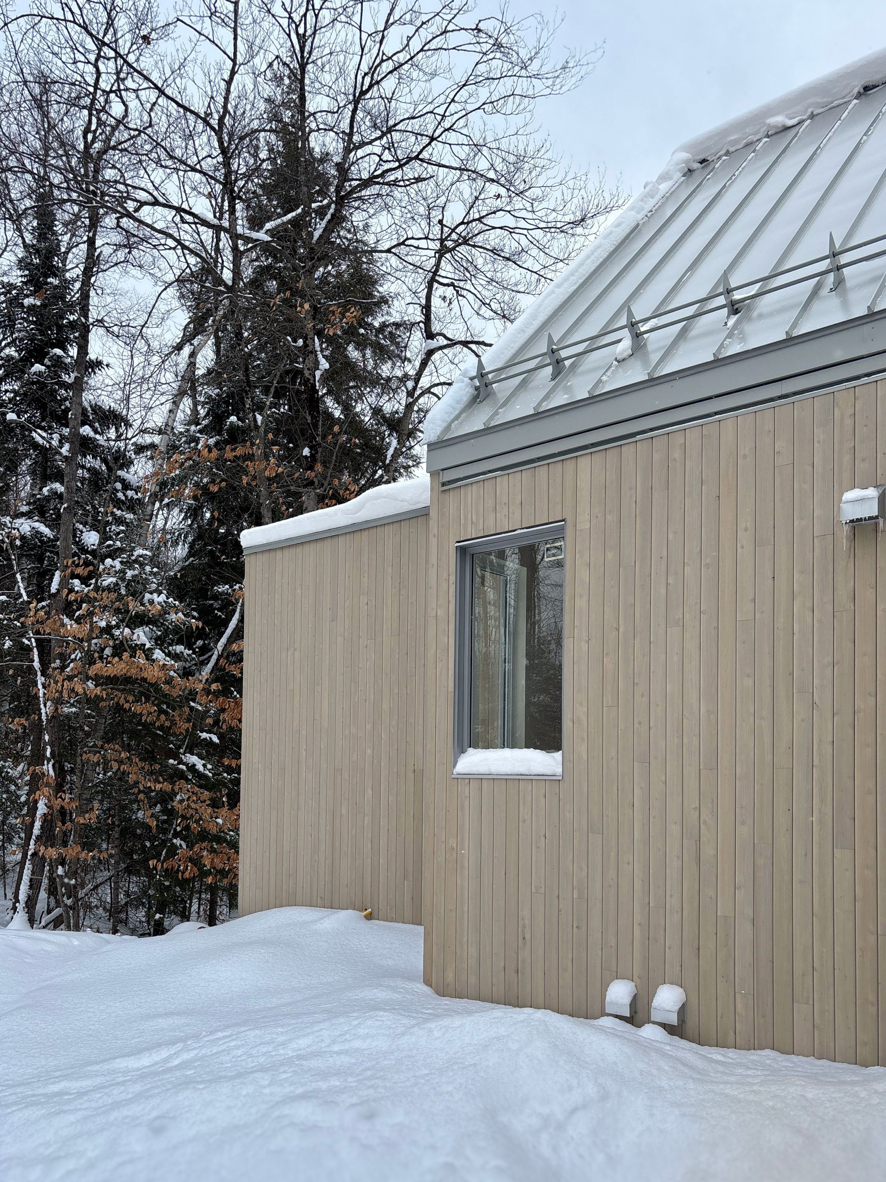 maison en construction, revêtment de bois pâle toiture d'acier grise environnement en nature et neige