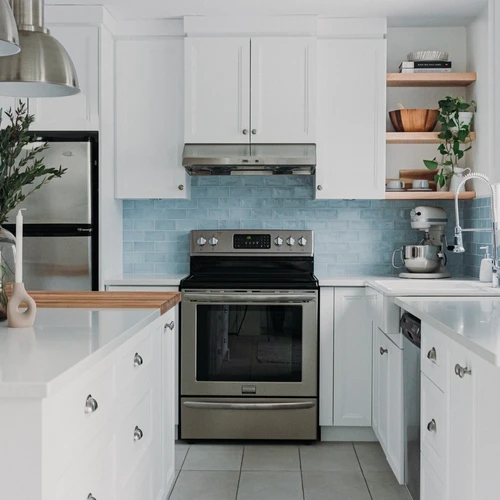 Cuisine blanche de style farmhouse avec dosseret de tuiles bleues et comptoir en bloc de boucher