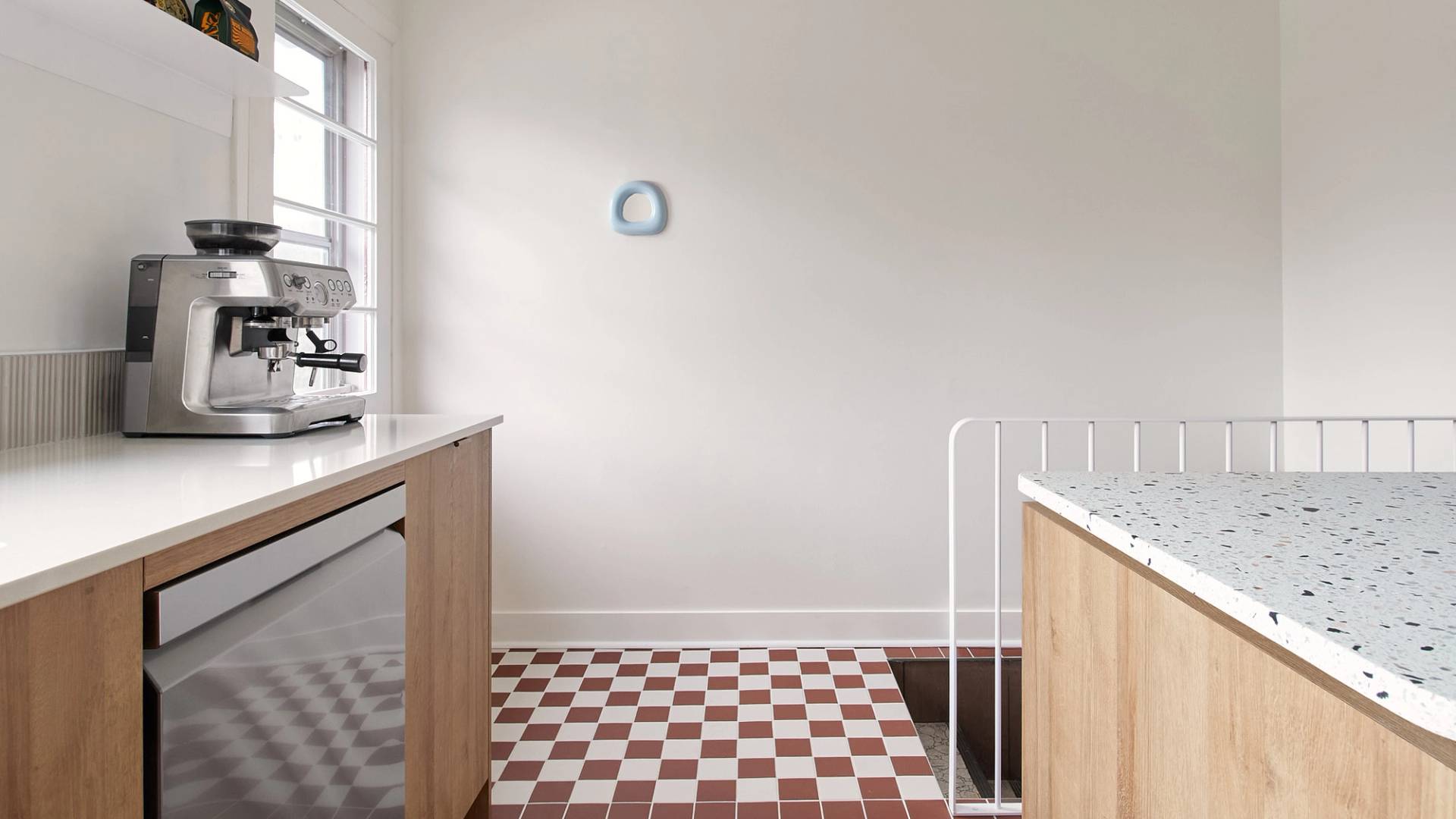 tuile carrée en damier rouge et blanche, miroir bleu, comptoir de terrazo, armoires de bois.