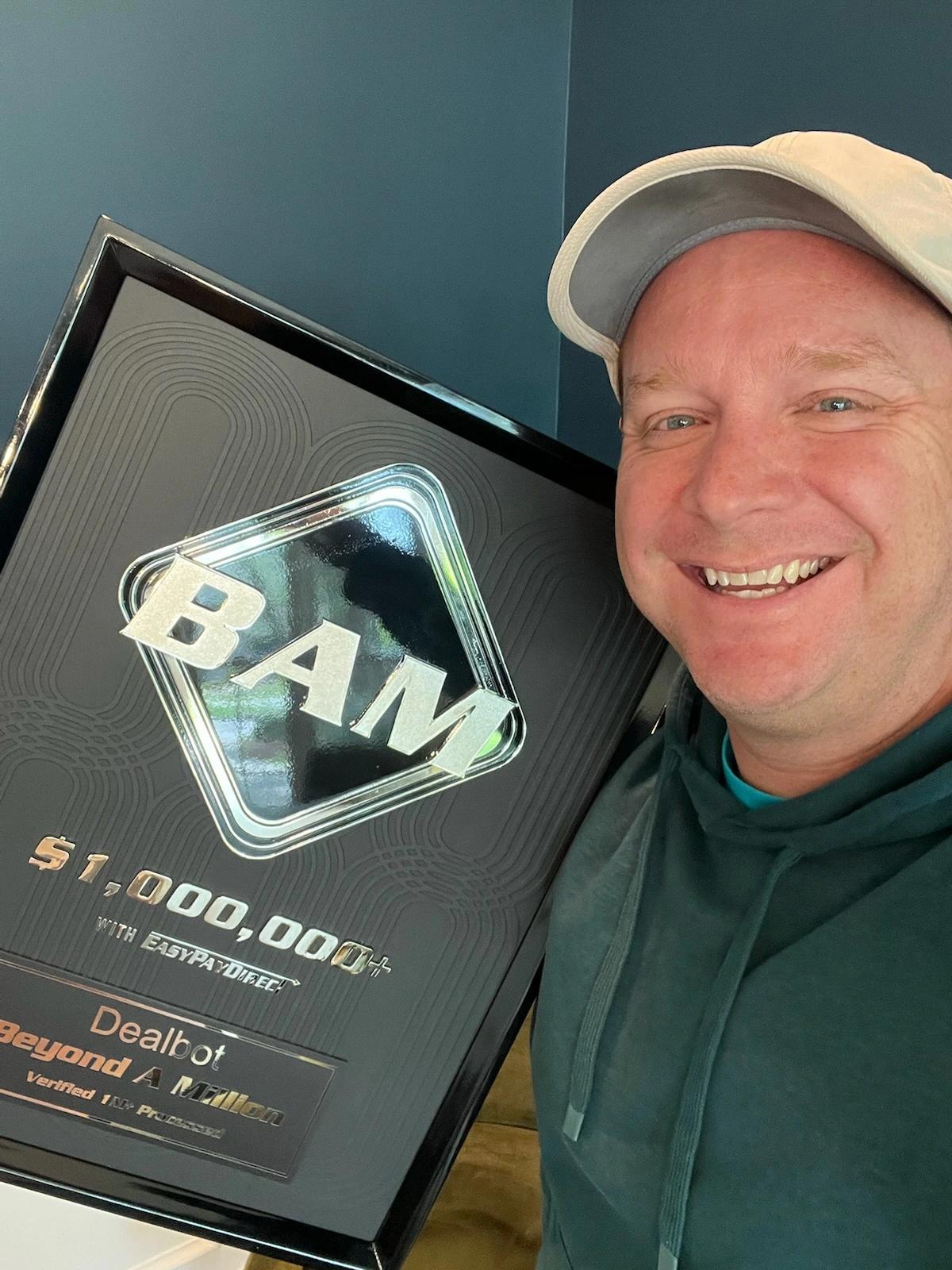 Dealbot founder holding a BAM $1M+ award plaque