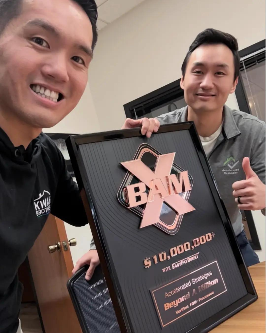 Accelerated Strategies founders holding a BAM X $10M+ award plaque