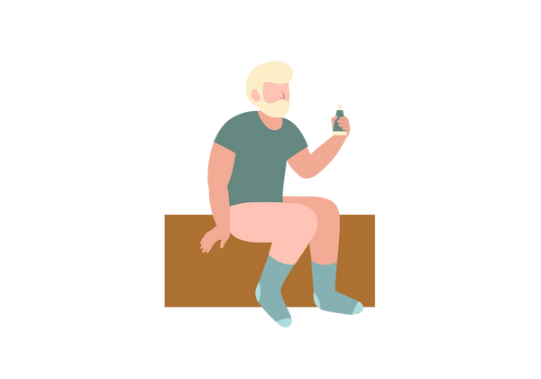 A man without pants sitting on a brown rectangle and holding a green bottle.