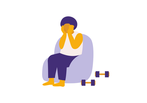 Persona sentada en una silla violeta claro con la cabeza entre las manos. Dos pesas se sientan en el suelo al lado de la silla.