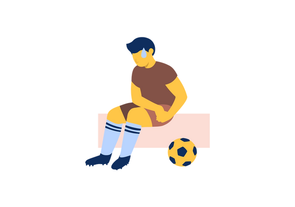 Un jugador de fútbol sentado en un bloque rosa tomándose la cadera. Hay una gota de sudor en la frente y un balón de fútbol en el suelo a la derecha.