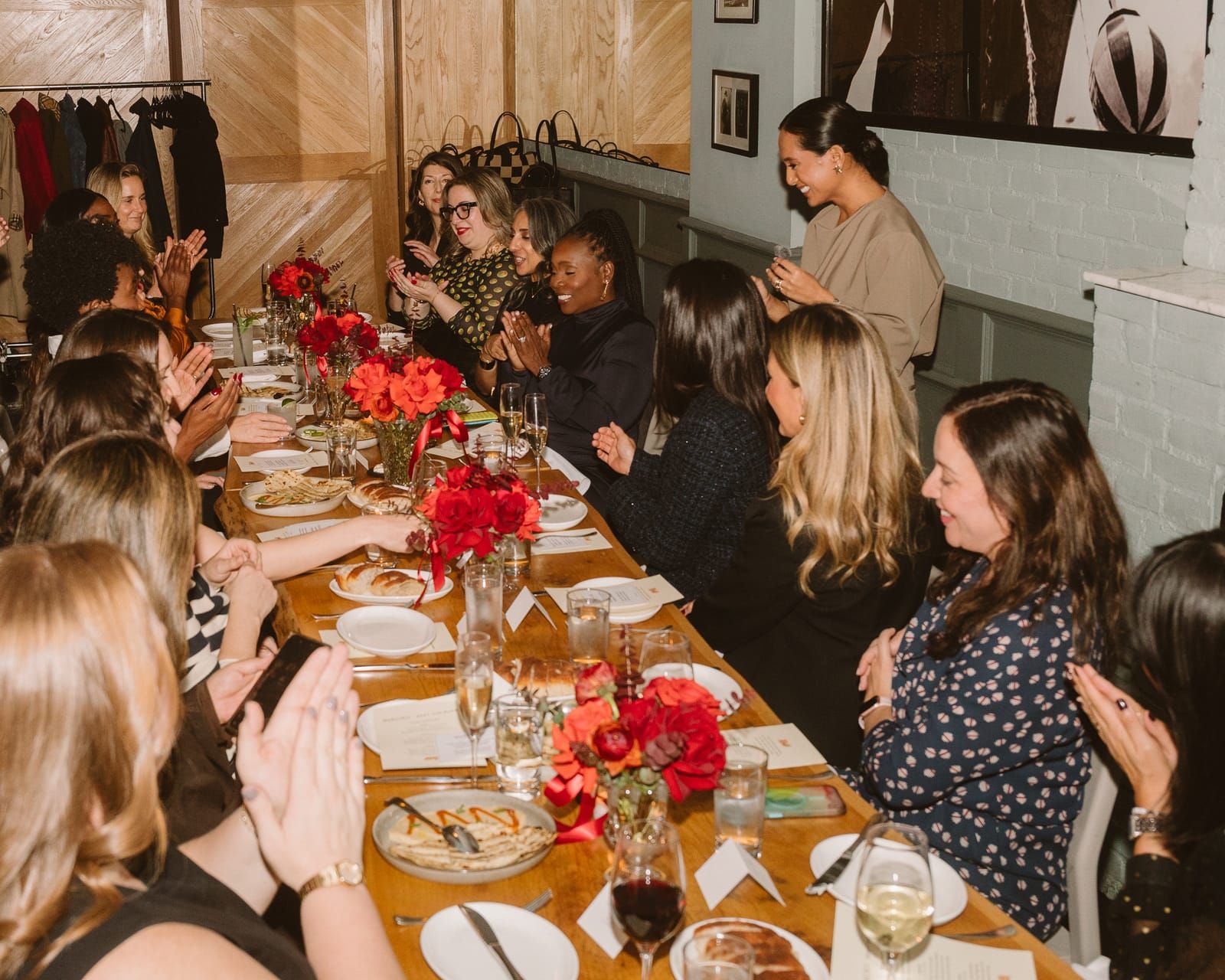 The long table at the Rent the Runway × Work Lunch dinner, guests mid-conversation over red roses