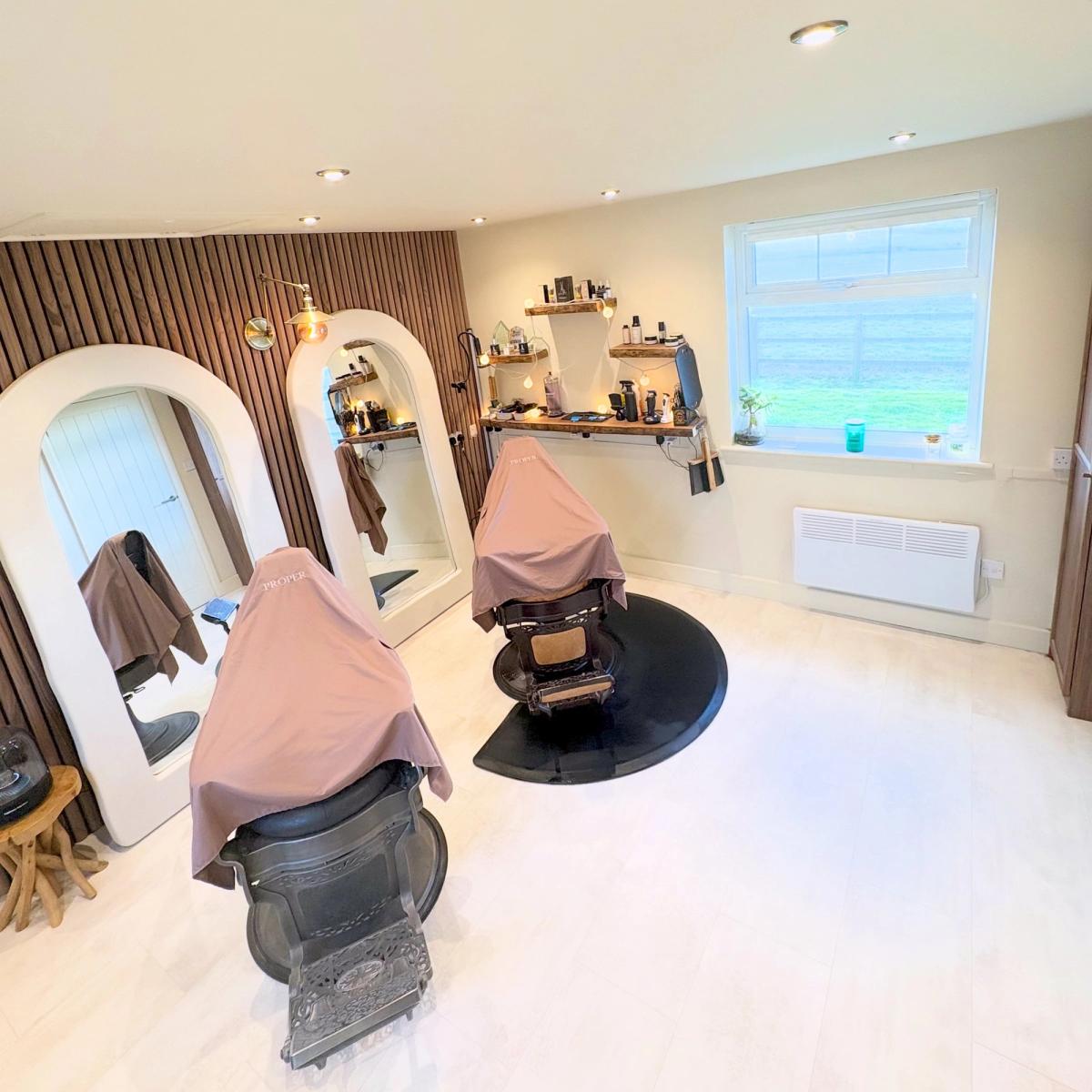 The Proper studio at Cooksoe Farm: two barber chairs, arched mirrors and a walnut slat wall