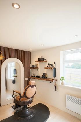 The studio’s arched mirror above a tan leather barber chair