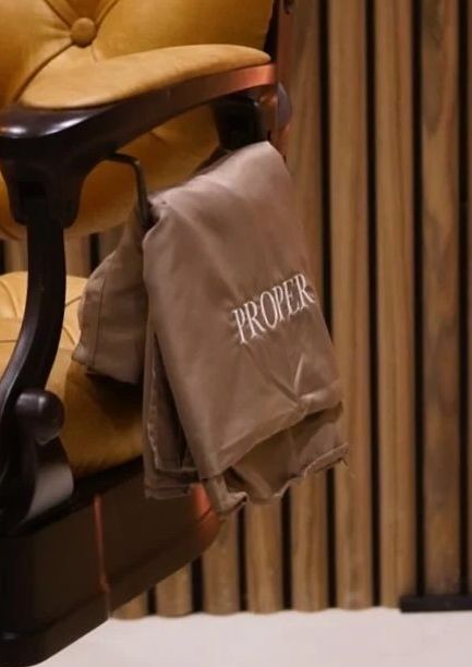 The Proper studio: a tan leather barber chair beside a walnut slat wall