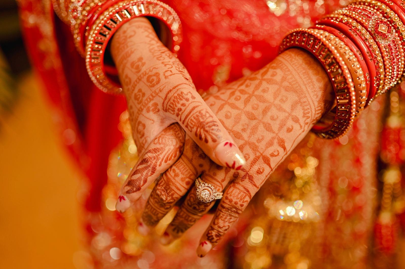 Close up of henna covered hands wearing ornate bangles at a South Asian wedding