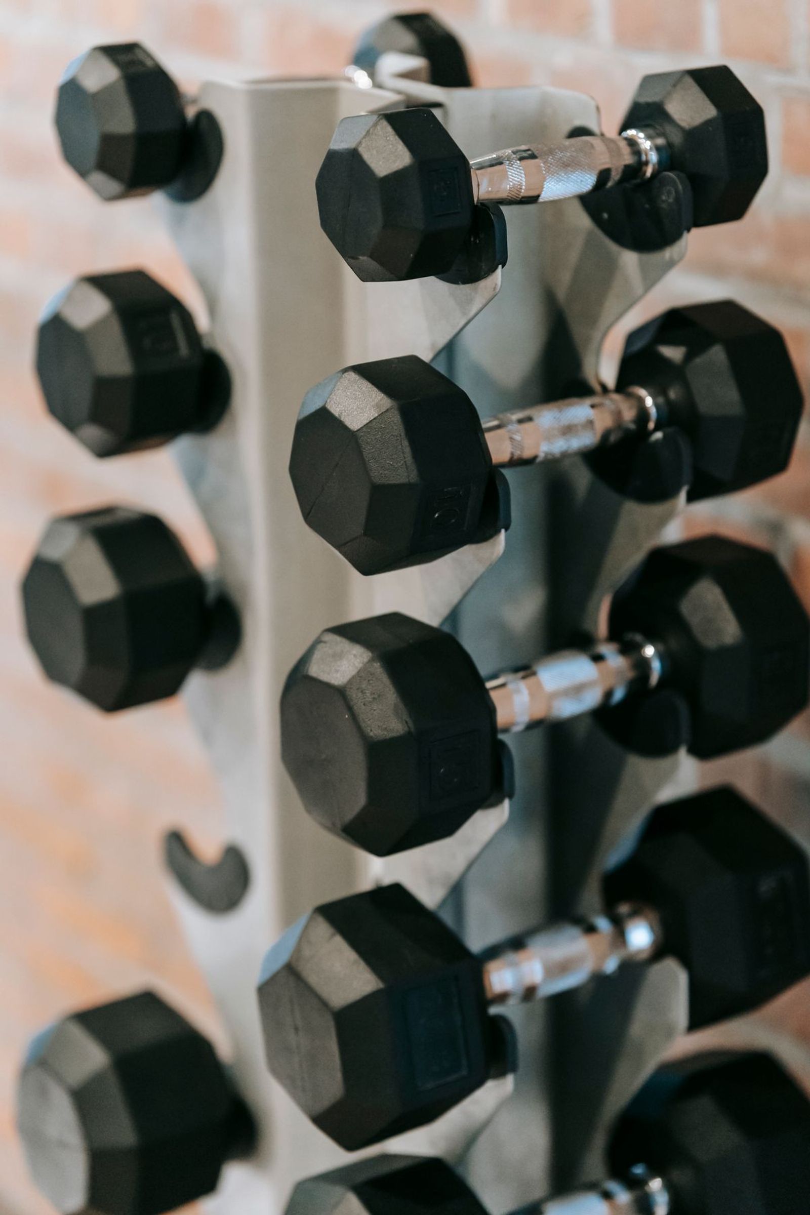 Hex dumbbells racked against a brick wall in a strength training area