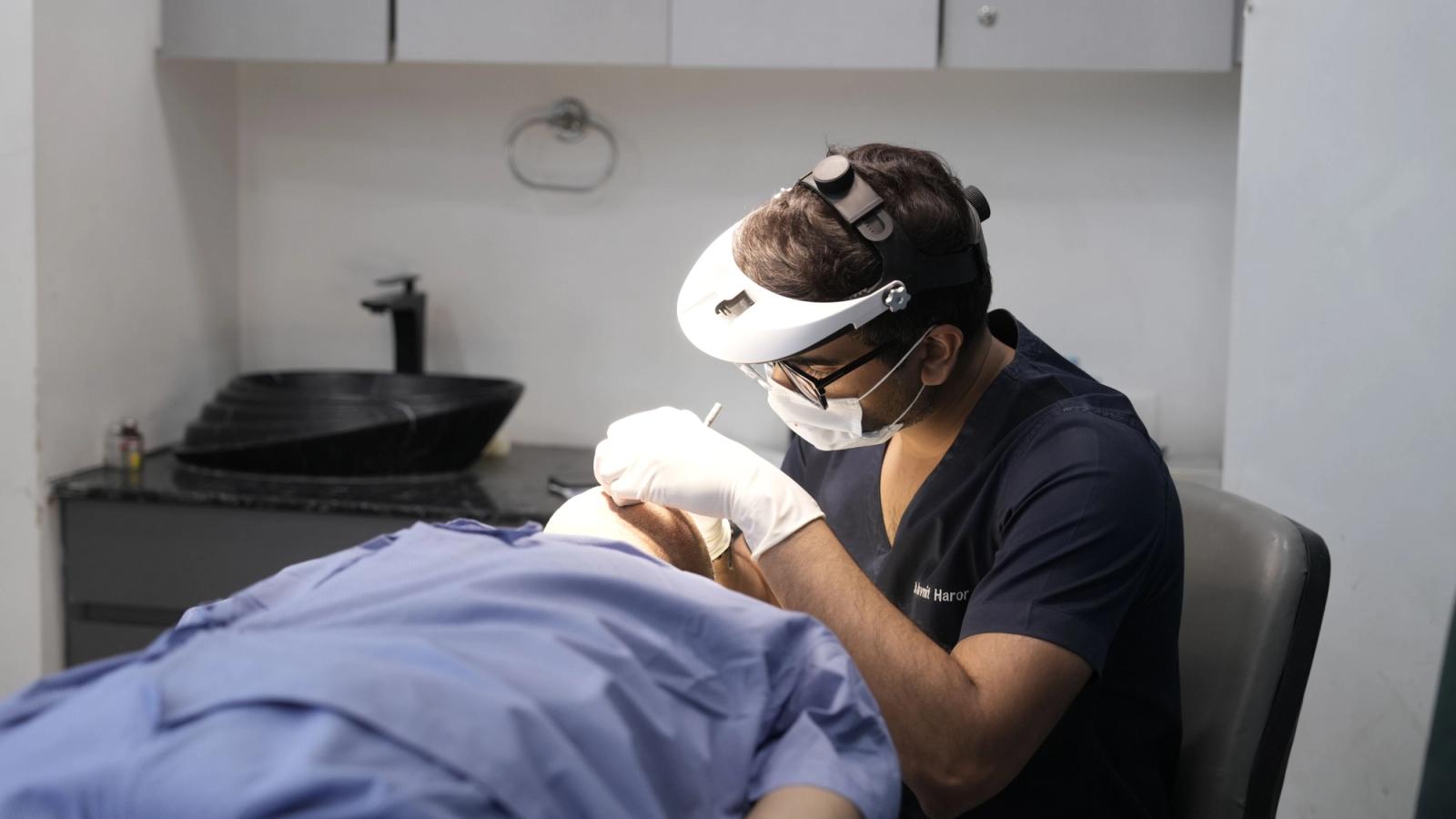 A dermatologist applying a skin treatment to a patient in a South Asian clinic