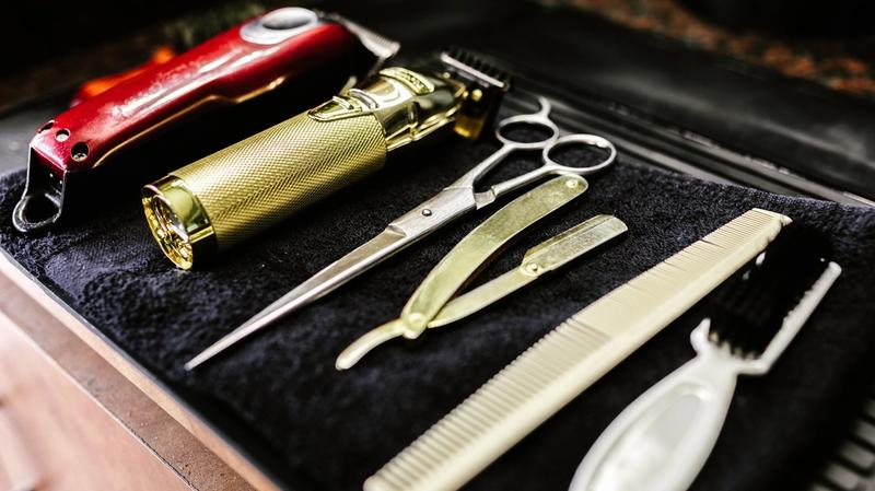 Barbershop tools including trimmers, scissors and razors arranged on a counter