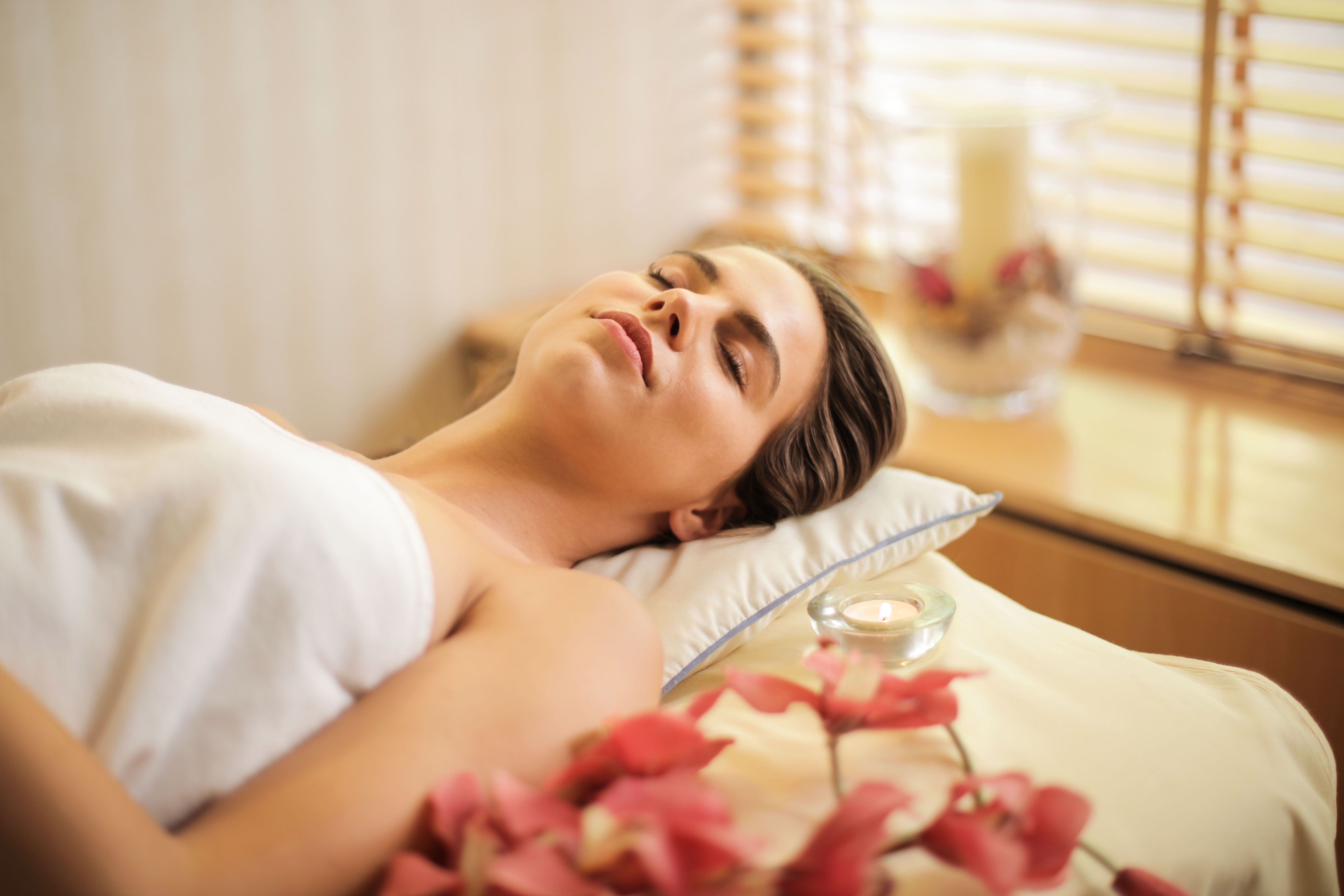 Serene spa room setup with a massage bed, rolled white towels, and ambient candles in Lahore