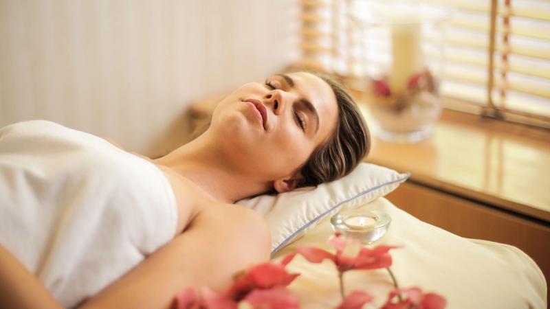 Serene spa room setup with a massage bed, rolled white towels, and ambient candles in Lahore
