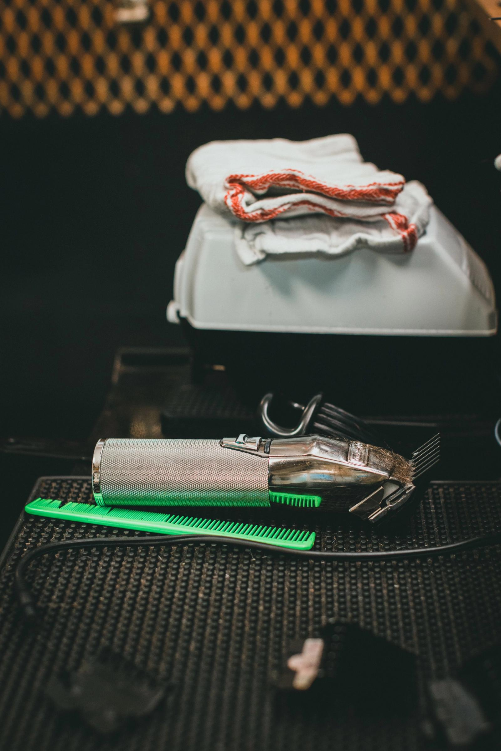Barber clippers, comb and towel laid out at a barbershop station