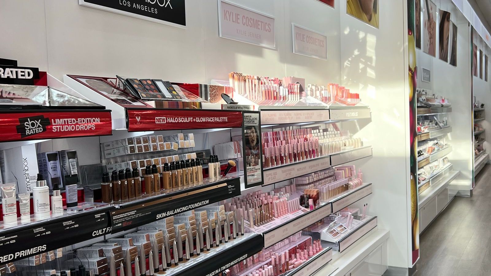 Brightly lit makeup aisle with rows of cosmetics on display shelves
