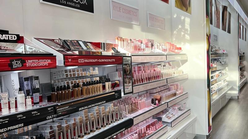 Brightly lit makeup aisle with rows of cosmetics on display shelves