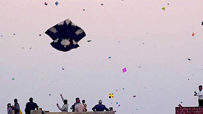 Kite fliers on a Lahore rooftop with dozens of kites in the sky during Basant
