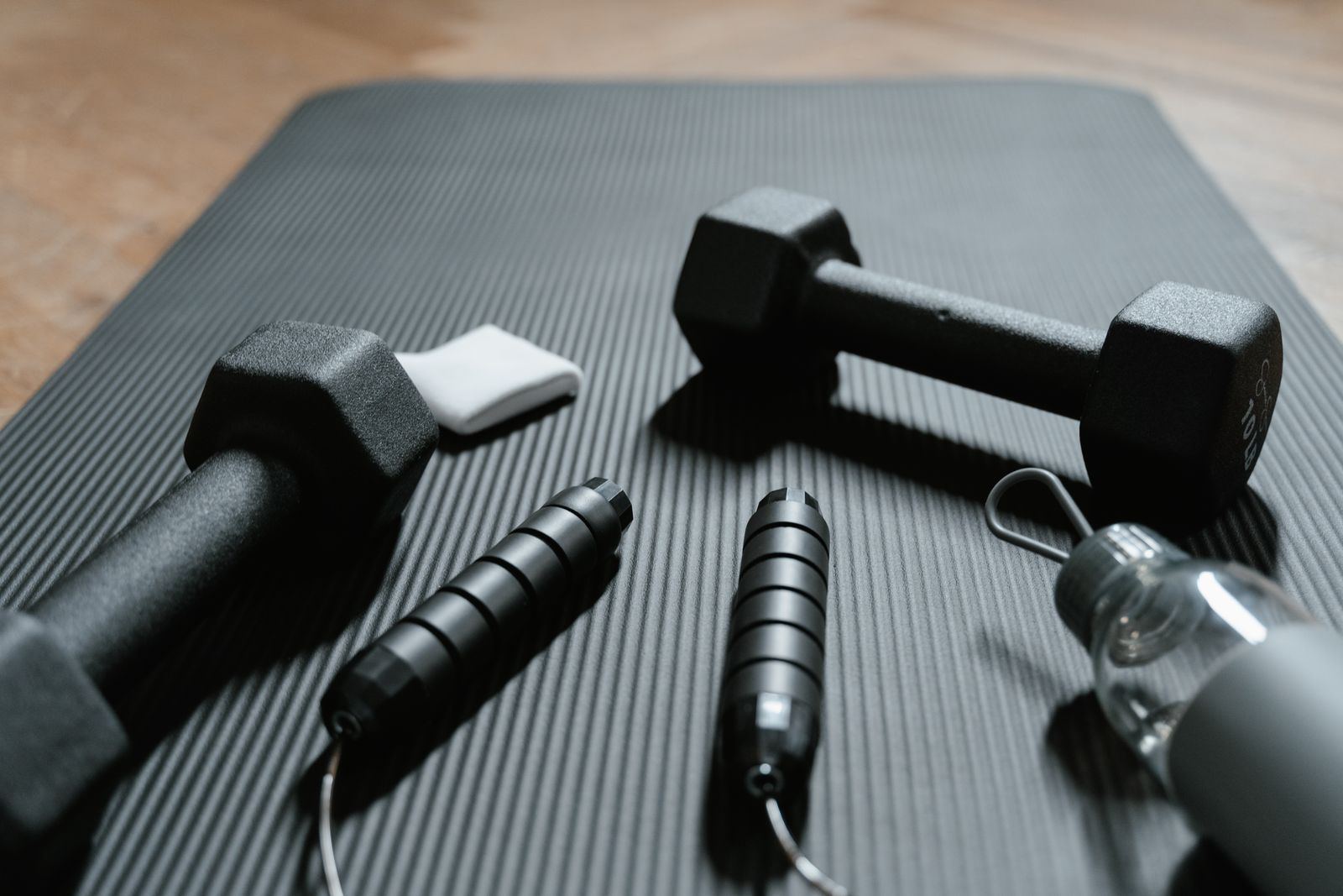 Dumbbells and a jump rope on a yoga mat at home