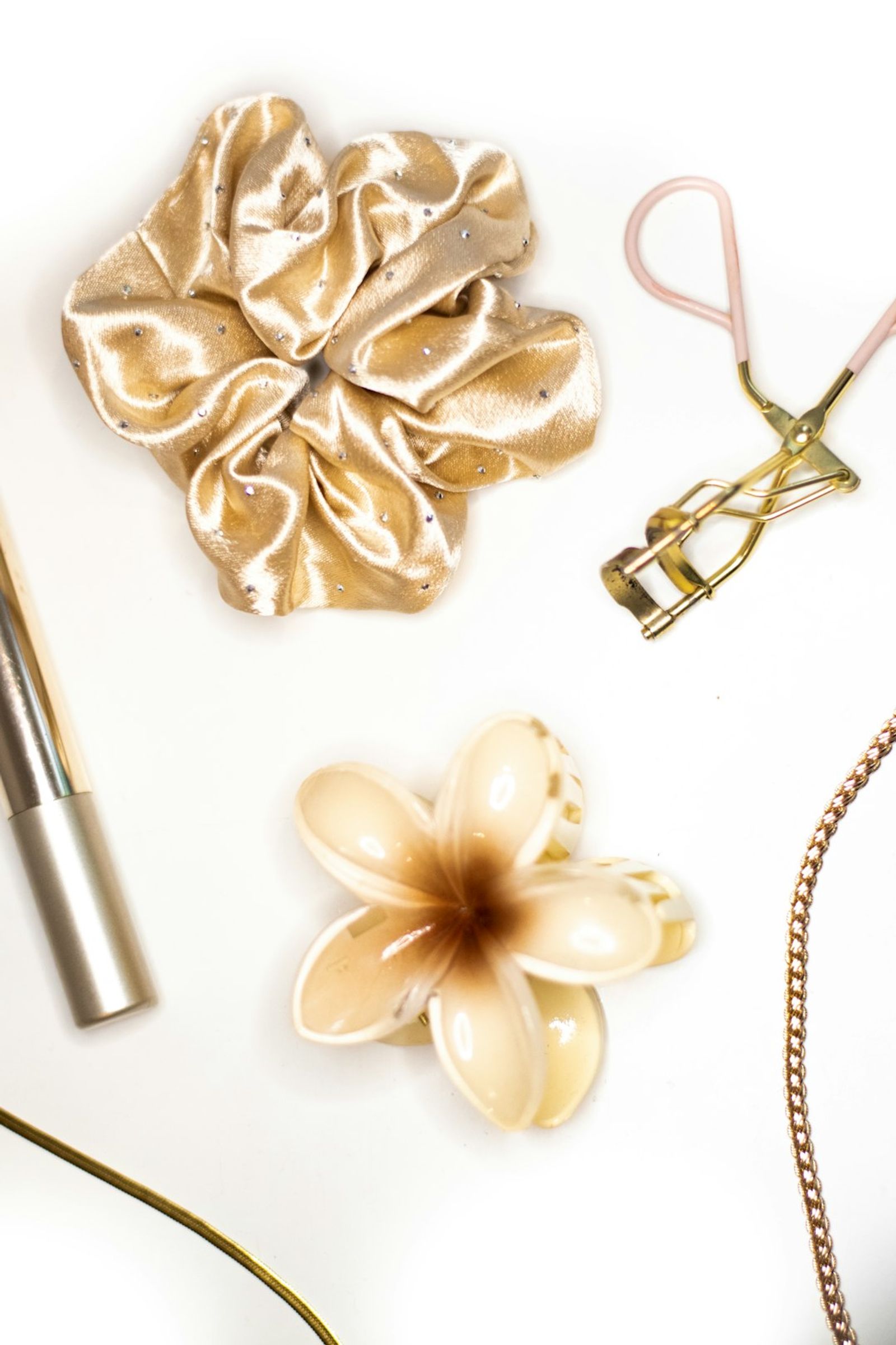 Lash curler and beauty styling tools on a clean white surface