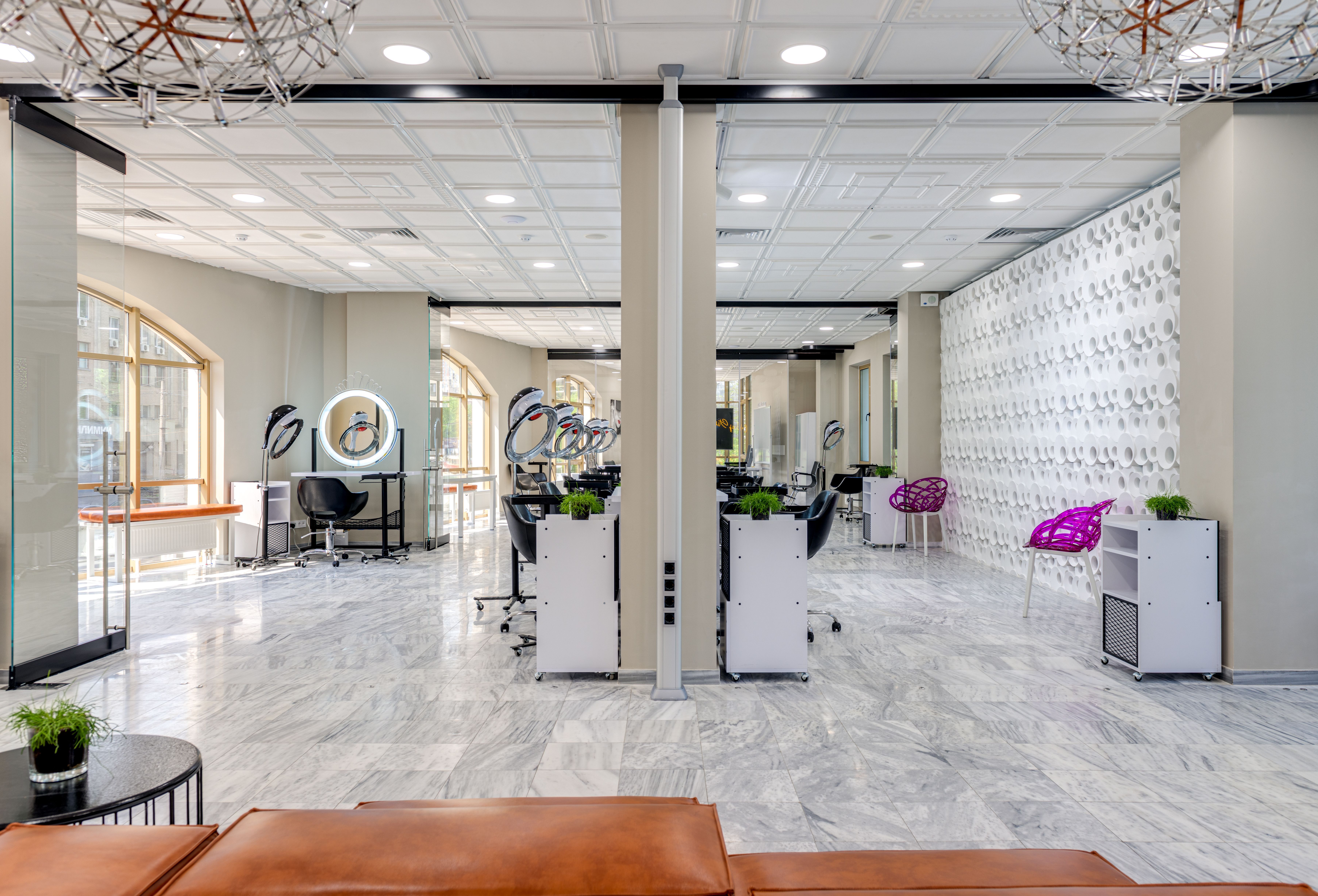 Empty modern beauty salon interior with styling chairs, large mirrors and bright lighting