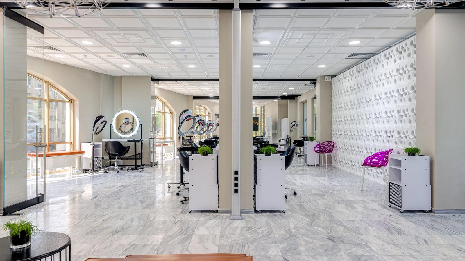 Empty modern beauty salon interior with styling chairs, large mirrors and bright lighting