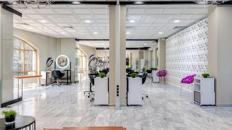 Empty modern beauty salon interior with styling chairs, large mirrors and bright lighting