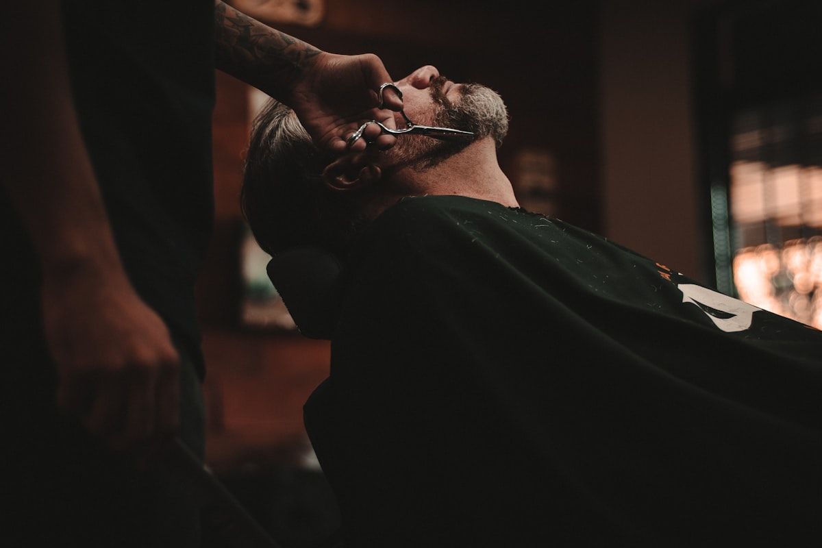 Barber tools including hair clippers, shears, combs and straight razor laid out on a salon workstation