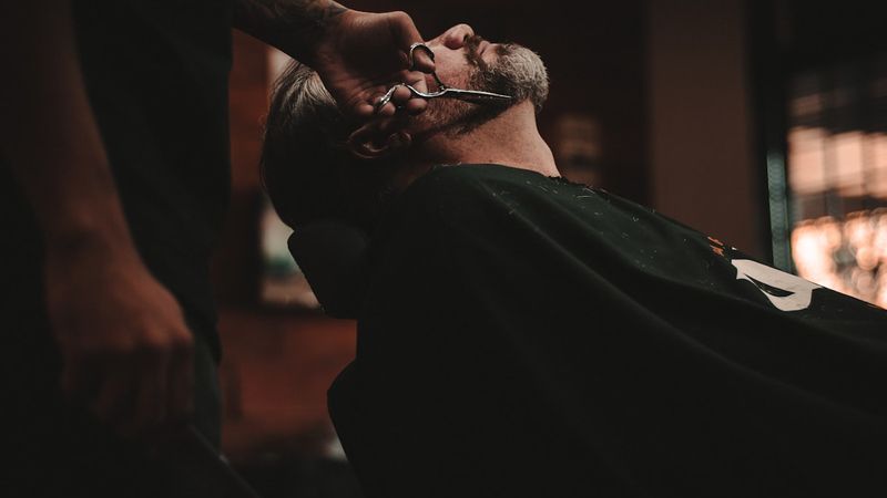 Barber tools including hair clippers, shears, combs and straight razor laid out on a salon workstation