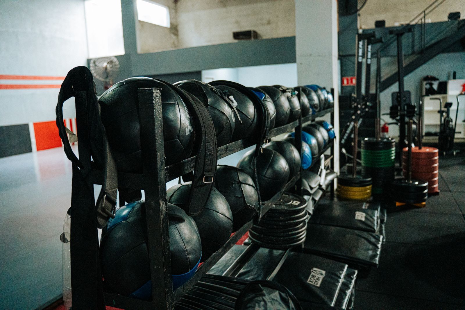 Medicine balls, weight plates and training rigs on the floor of a fitness gym