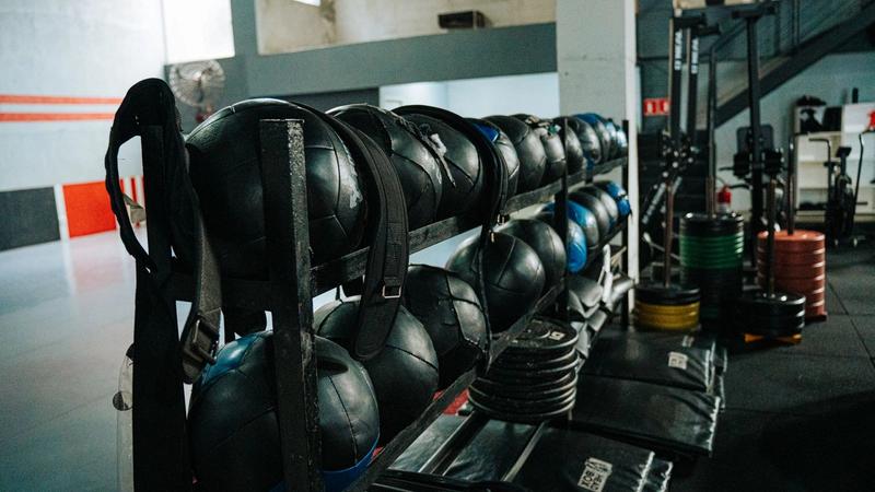 Medicine balls, weight plates and training rigs on the floor of a fitness gym