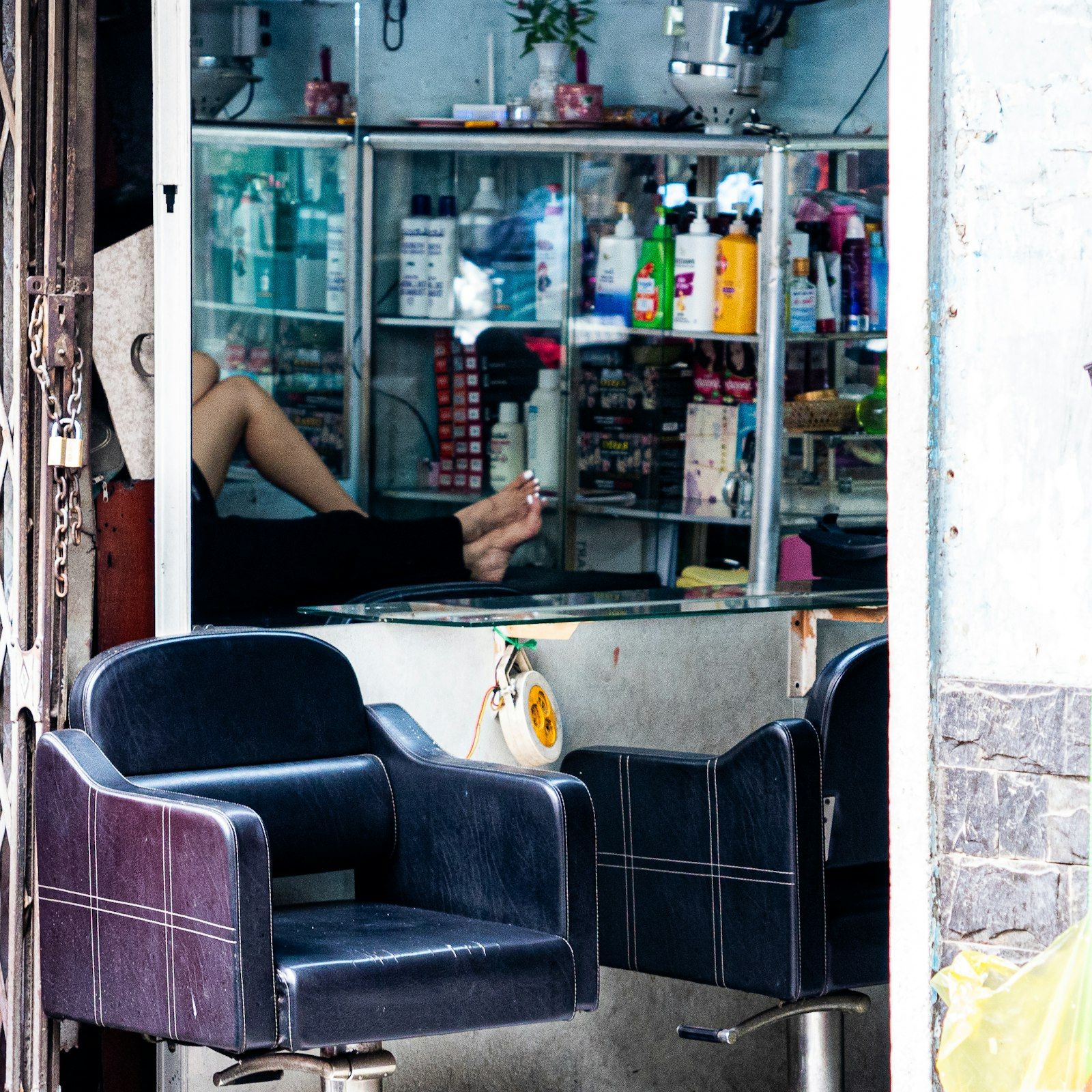 Two chairs outside a salon with product shelves behind them