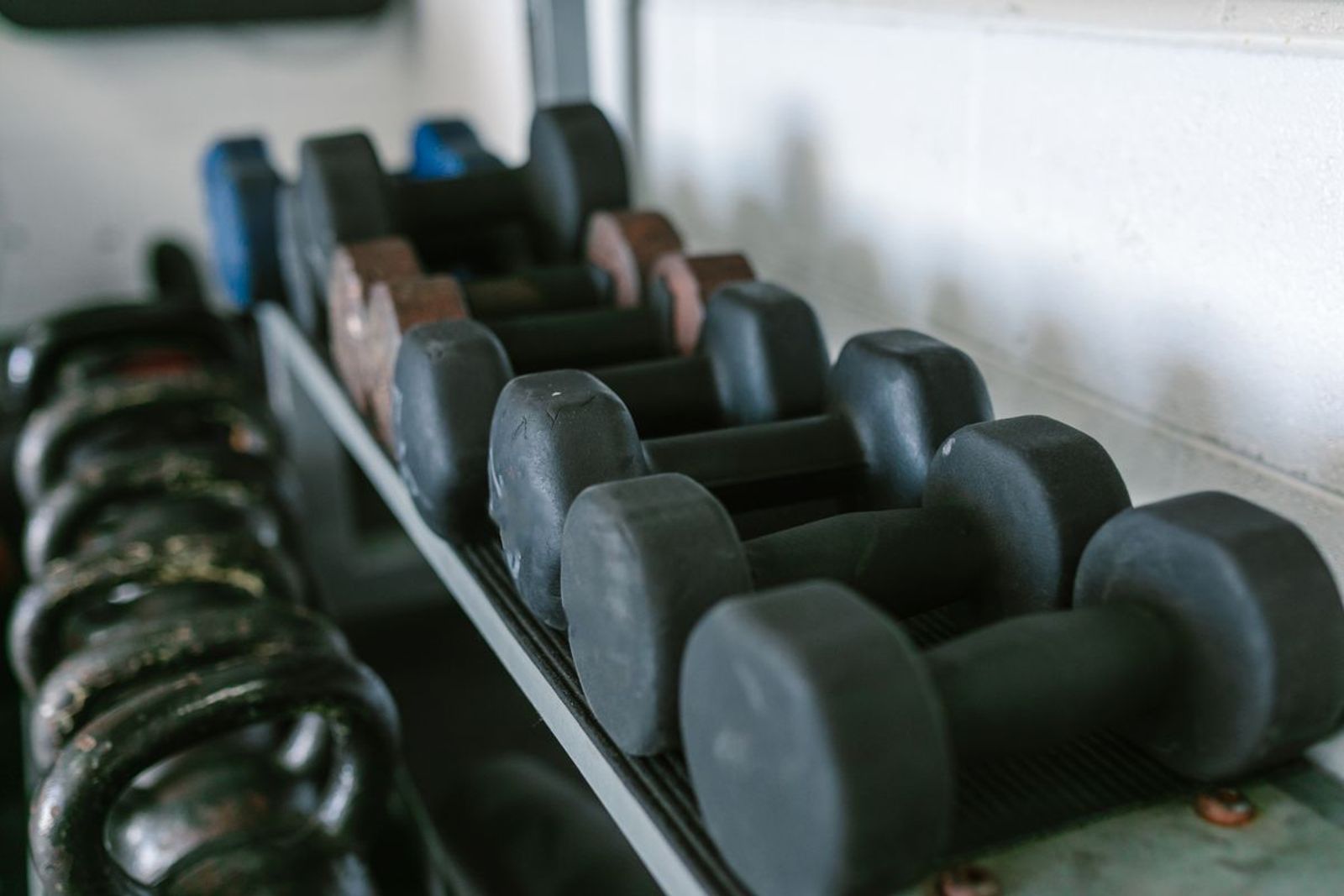 Rack of black neoprene dumbbells in a working gym