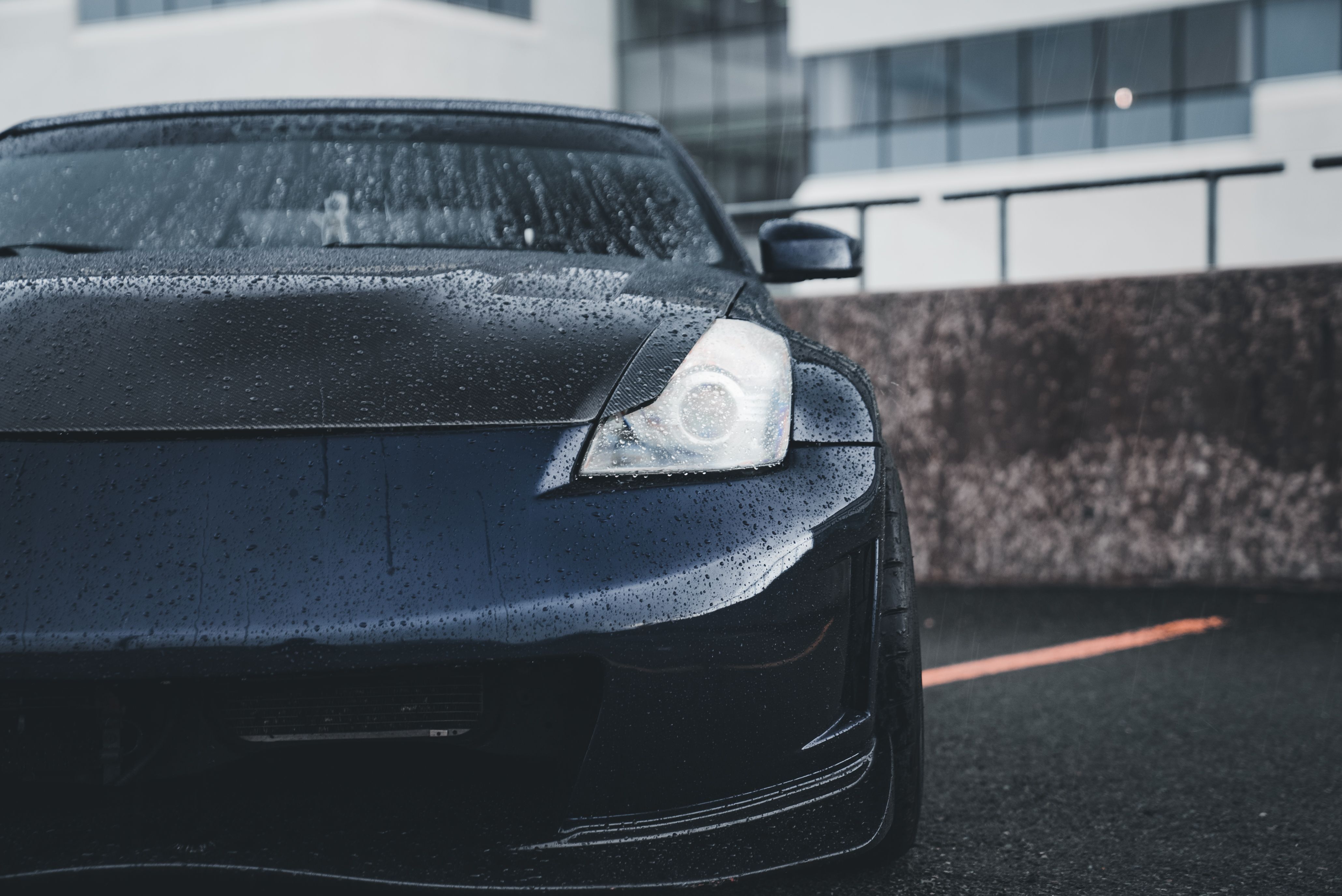 Water beading on the glossy black hood of a freshly detailed and protected car