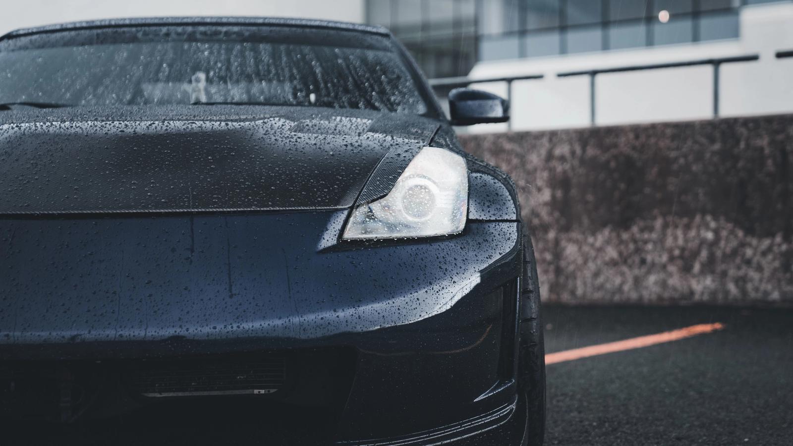 Water beading on the glossy black hood of a freshly detailed and protected car