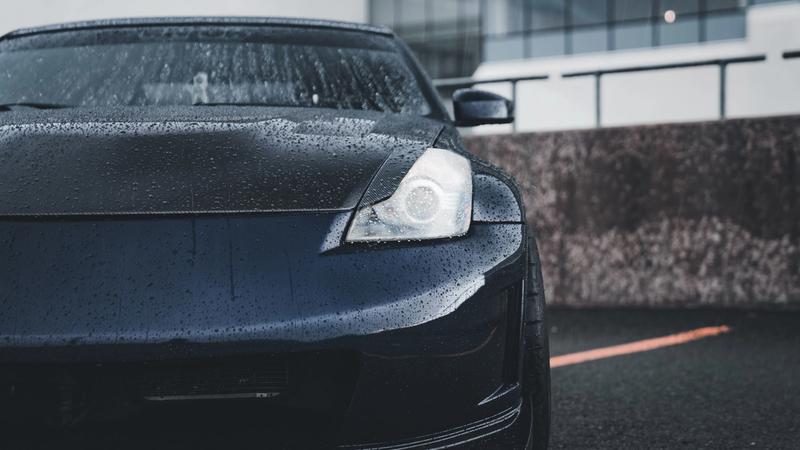 Water beading on the glossy black hood of a freshly detailed and protected car