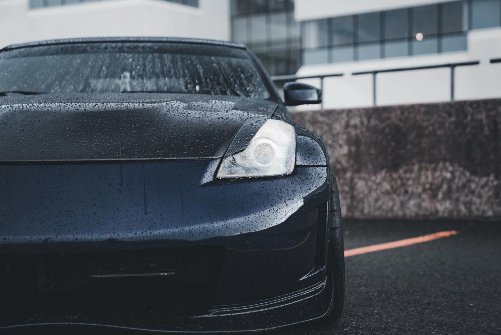 Water beading on the glossy black hood of a freshly detailed and protected car