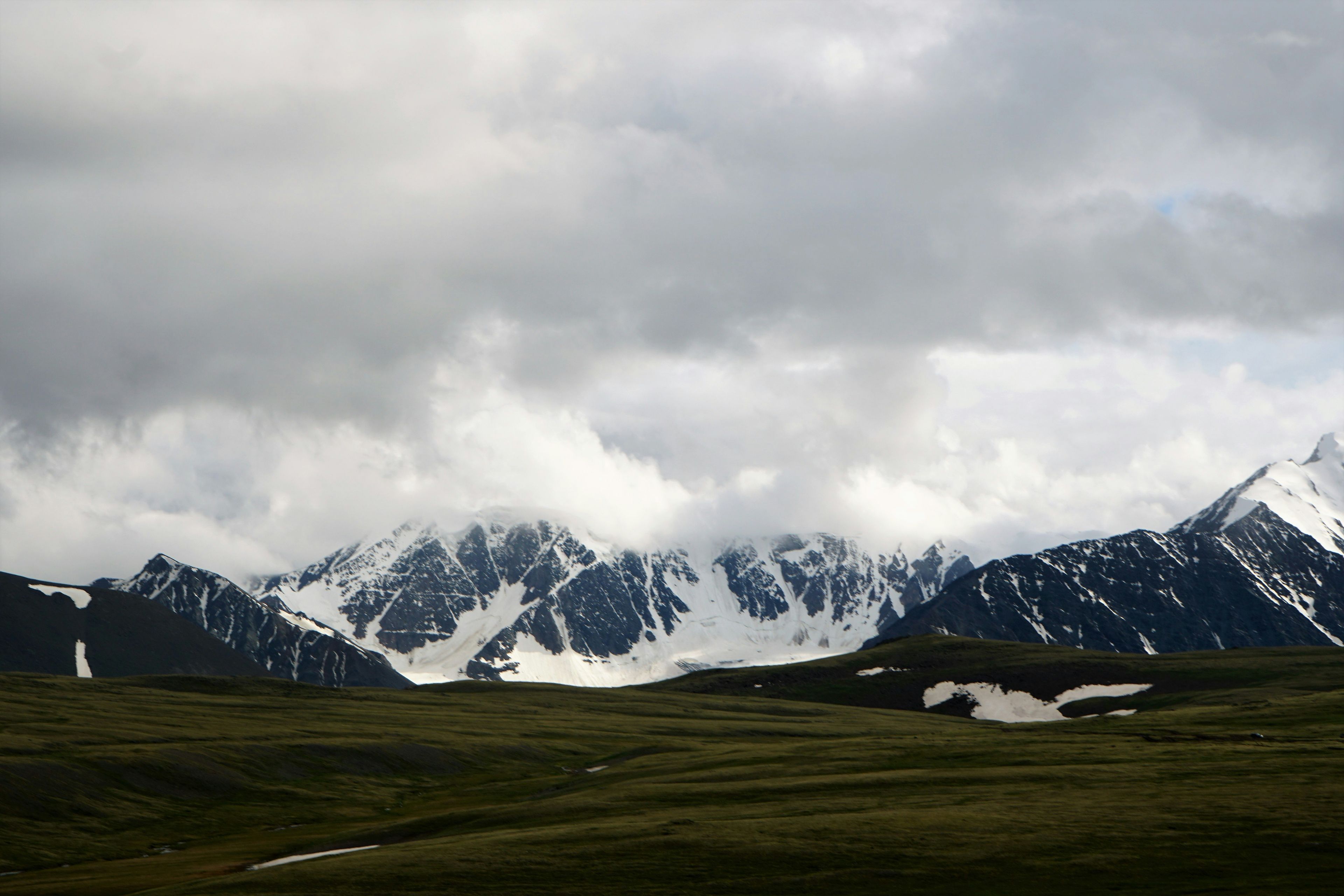snow covered mountains under cloudy sky during daytime