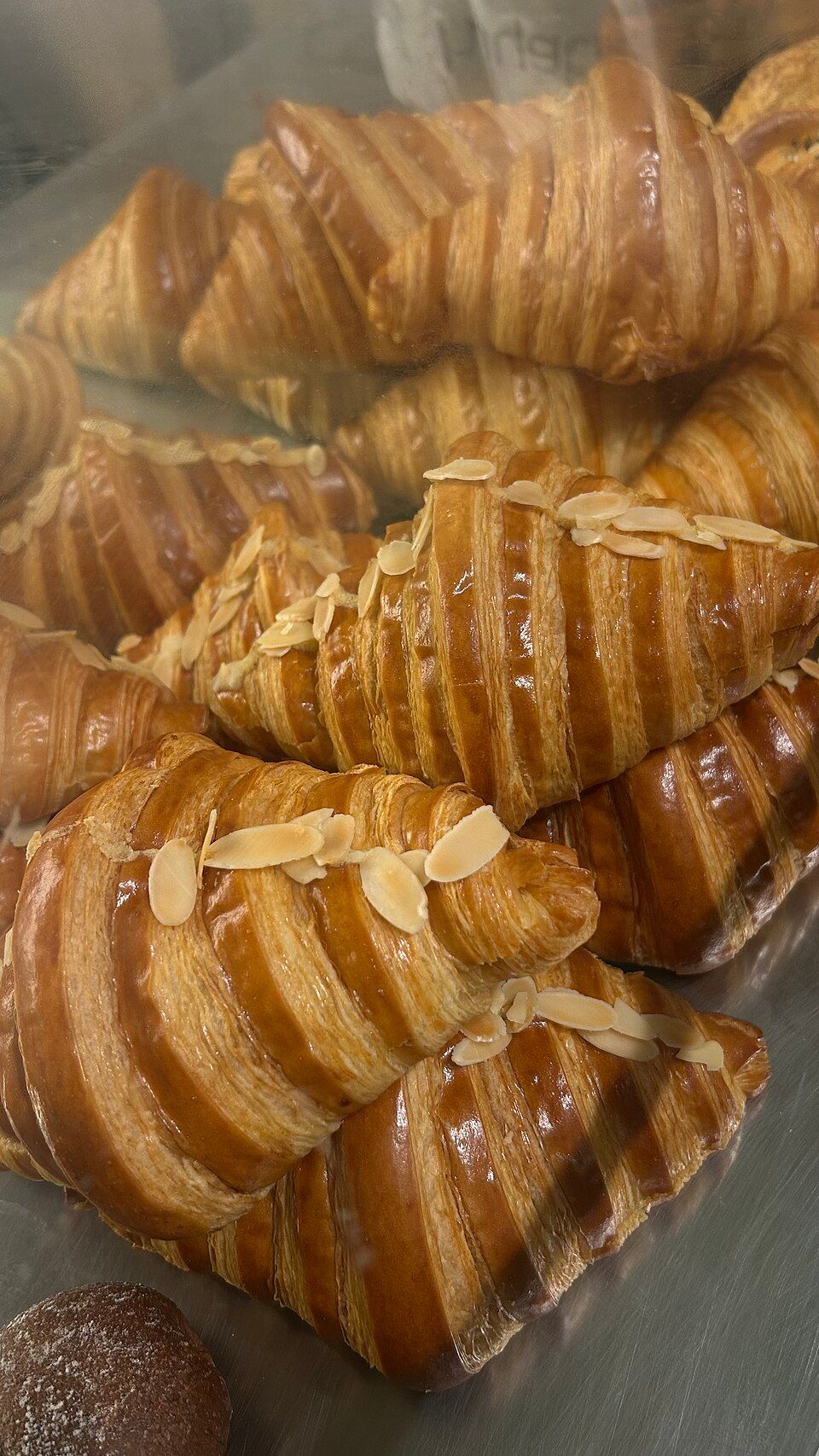 Croissant de almendra: Hojaldre de mantequilla relleno de crema de almendra, tostado al momento.